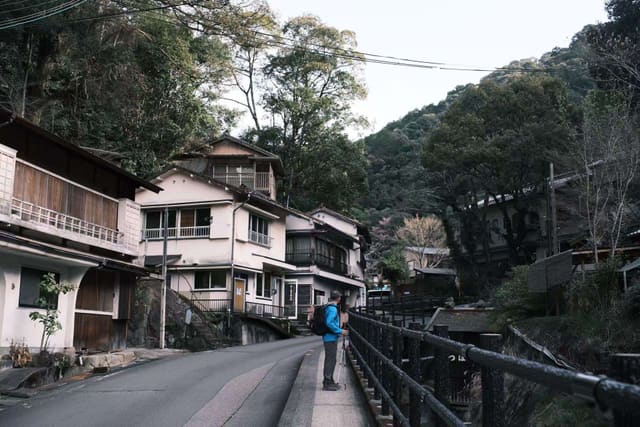 James Moore with a backpack and trekking poles, pausing on a mountain village road